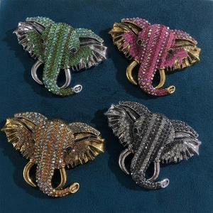 Detail of four colorful elephant brooches with rhinestones on a dark blue velvet surface