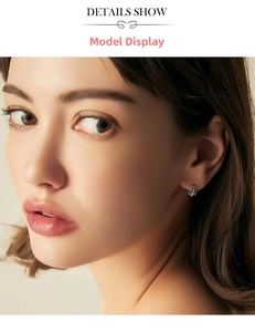 Detailed close-up of a silver leaf-shaped hoop earring worn by a female model