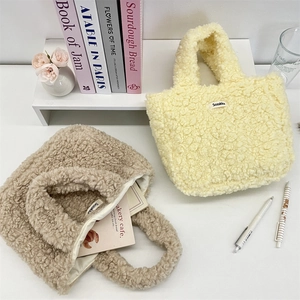 Detail view of plush fleece teddy tote bags in beige and brown with brand woven label