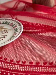 Close-up of red Christmas lace tablecloth with intricate heart and geometric patterns