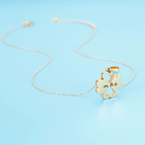 Macro shot of gold clover pendant with hollow heart and engraved mãe text for Mother's Day