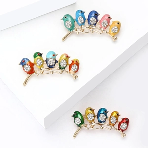 Colorful enamel bird brooches with rhinestones set on a golden branch display