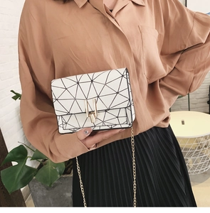 Detail of white leather shoulder bag with black geometric lines and gold chain strap