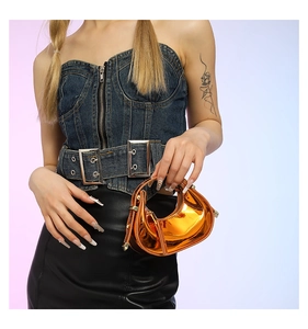 Detail of trendy orange laser patent leather handbag with stylish metallic rivets