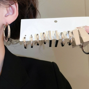 Detailed set of geometric silver earrings in round and square shapes worn by a model