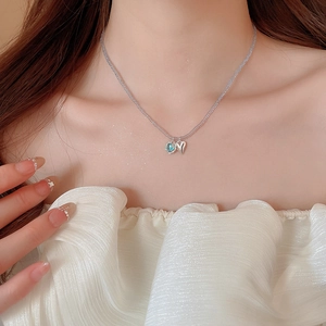 Close-up of heart pendants on light purple beaded chain worn by a model in soft lighting