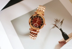 Gros plan sur la montre en or rose avec cadran rouge dégradé et index en strass