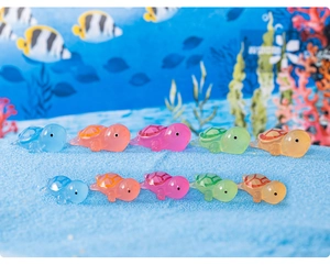 Detailed view of ten colorful resin mini turtles arranged on blue sand for aquariums