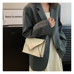 Detail of a chic cream white envelope bag with silver V-shaped buckle and chain strap