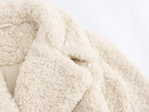 Detailed close-up of soft faux fur collar and shoulder on cream white winter coat