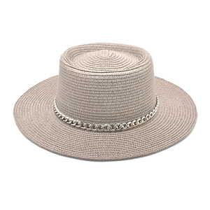 Detail of silver chain accent on wide-brimmed khaki straw hat with woven texture