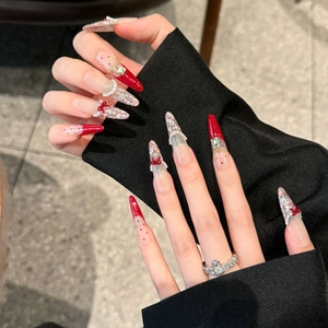 Elegant long pointed red press-on nails with bow, pearls, and silver glitter accents