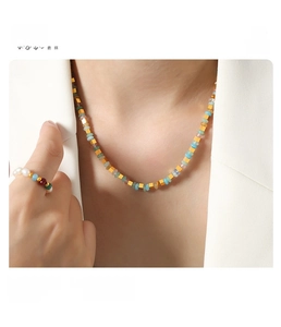 Détail de perles abaque colorées et d'entretoises cubiques en acier titane sur un collier