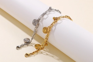 Detail of double-layer stainless steel bracelets with sunburst charm in gold and silver