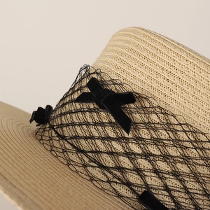 Beige flat top straw hat with black mesh veil and velvet bow for summer vacation