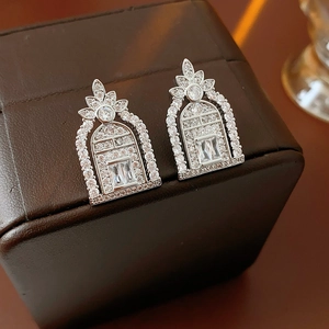 Macro shot of silver earrings with hollow geometric design and clear zircon stones