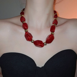 Macro shot of red acrylic chunky beads with glitter finish and golden metal spacers
