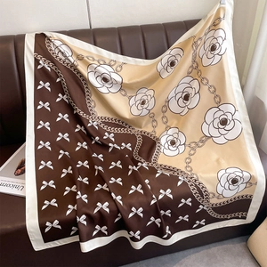 Détail d'un foulard carré en satin de soie avec fleurs de camélia et nœuds imprimés