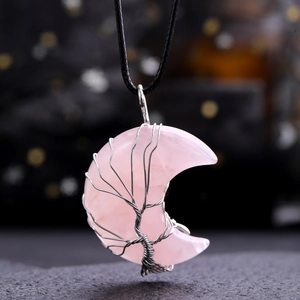 Macro shot of pink quartz moon pendant with silver wire tree of life on black cord