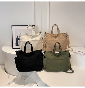 Detail of four corduroy tote bags in cream, khaki, black and green on a minimalist stand