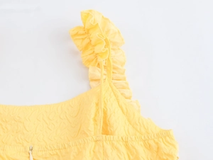 Close-up of ruffled shoulder straps and embossed texture on the yellow maxi dress