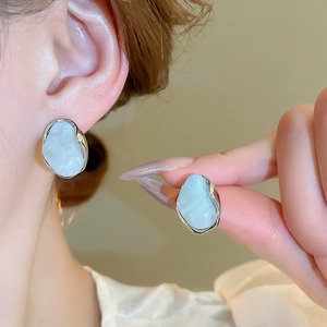 Détail macro de boucles d'oreilles fleurs argentées avec résine texturée bleu clair
