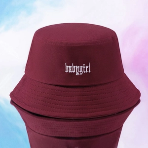 Dettaglio del ricamo bianco babygirl su un cappello a secchiello in tela bordeaux