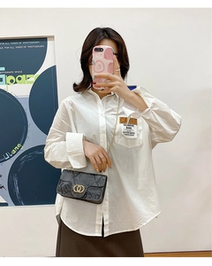 Detail of white cotton shirt paired with a chic faux snakeskin leather crossbody bag