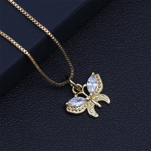 Macro detail of gold butterfly pendant with crystals and box chain on black leather