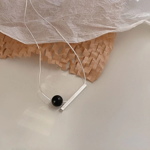 Macro shot of 925 silver tube and black onyx bead pendant on a sleek snake chain