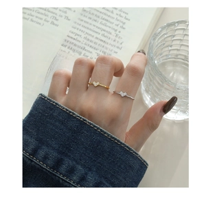 Detail of silver and gold V-shaped zircon rings worn while reading a book