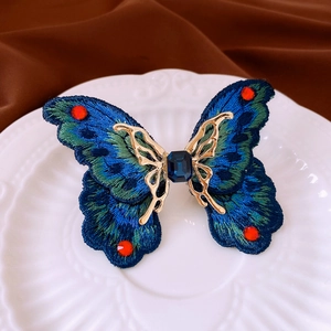 Macro detail of embroidered butterfly ring with blue gemstone and sparkling crystals