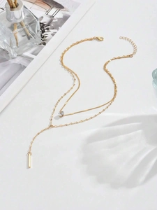 Detailed view of elegant gold Y-shaped double necklace with crystal and metal bar pendant