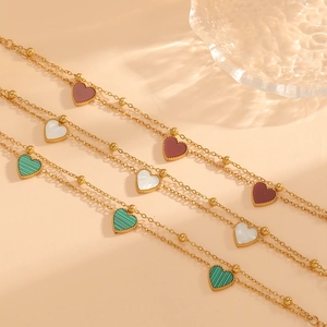 Three heart shell charms on double-layer gold chain bracelets in red, white, and green