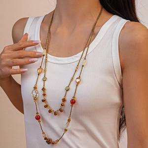 Long beaded necklace with amber and red glass crystals on a model wearing white