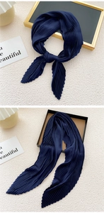 Detail showing the pleated texture and draping effect of the navy blue satin scarf