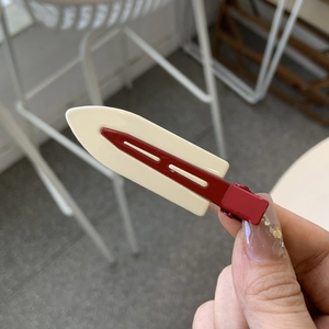 Retro cream and deep red metal hair clip shown in a hand-held view for daily hair styling