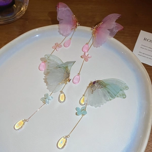 Detail of elegant butterfly tassel earrings with colorful beads and silk wings on a tray