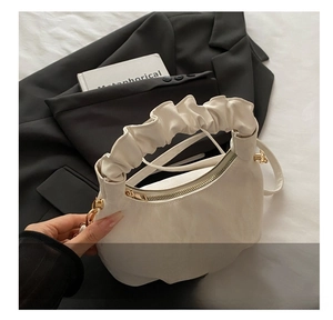 Detailed shot of white cloud bag with pleated handle and elegant golden metal hardware