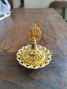 Detailed top view of golden hollow-out Middle Eastern resin incense burner on wood