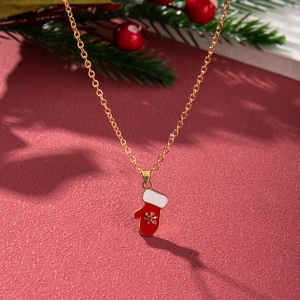 Close-up of golden necklace with red and white Christmas glove pendant and snowflake detail