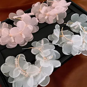 Boucles d'oreilles fleurs en tulle avec perles de cristal sur plateau en velours noir