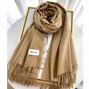Close-up of camel cashmere scarf with elegant tassels and Gerunsi brand woven label