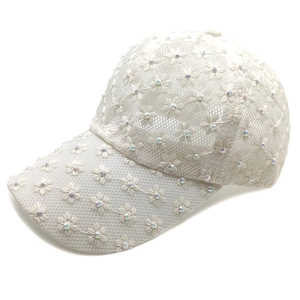 Detailed macro view of white floral lace embroidery and rhinestones on the baseball cap