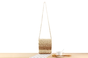 Detail of handmade woven straw bag with gradient beige and brown texture on wood