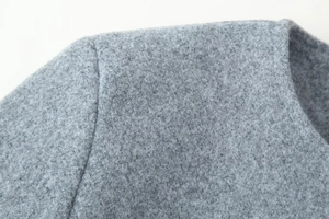 Detailed view of grey wool coat neckline and shoulder stitching with soft fabric texture