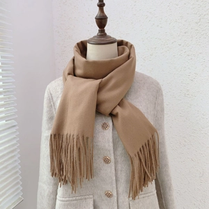 Detail of soft camel cashmere-like scarf with tassels styled on a mannequin