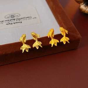 Détails macro de boucles d'oreilles carpe koï dorées avec finition métal texturé
