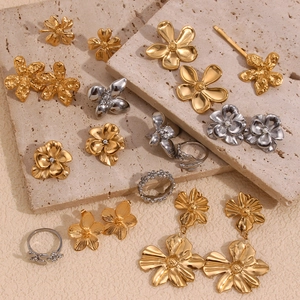 Macro shot of 18K gold and silver floral jewelry collection with zircons on beige stone