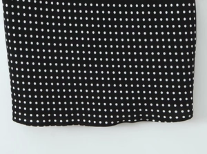 Detail view of the black and white polka dot fabric and hem stitching of the dress